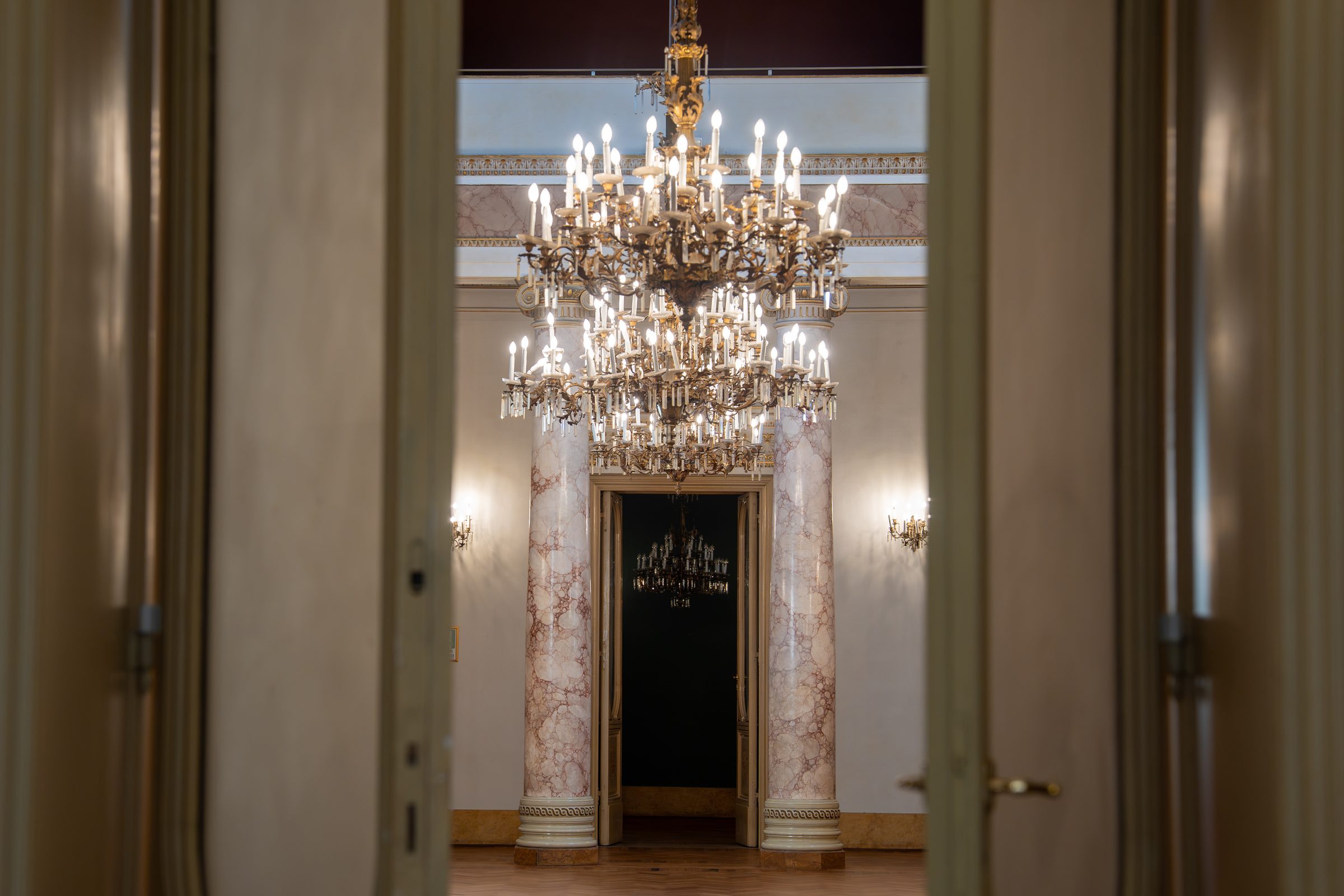 Il salone di Palazzo Le Stanze a Pistoia visto in prospettiva attraverso una porta, con lampadario.