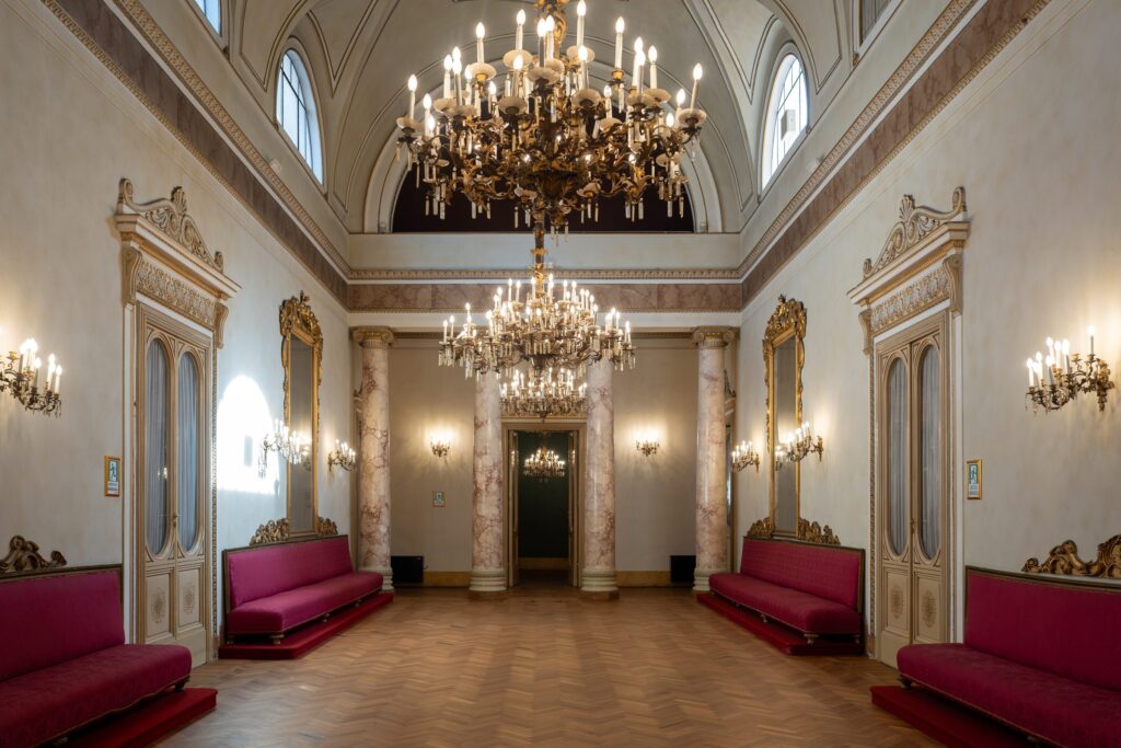 Il salone di Palazzo Le Stanze a Pistoia con lampadari e lunghi divani, pronto per una cerimonia.